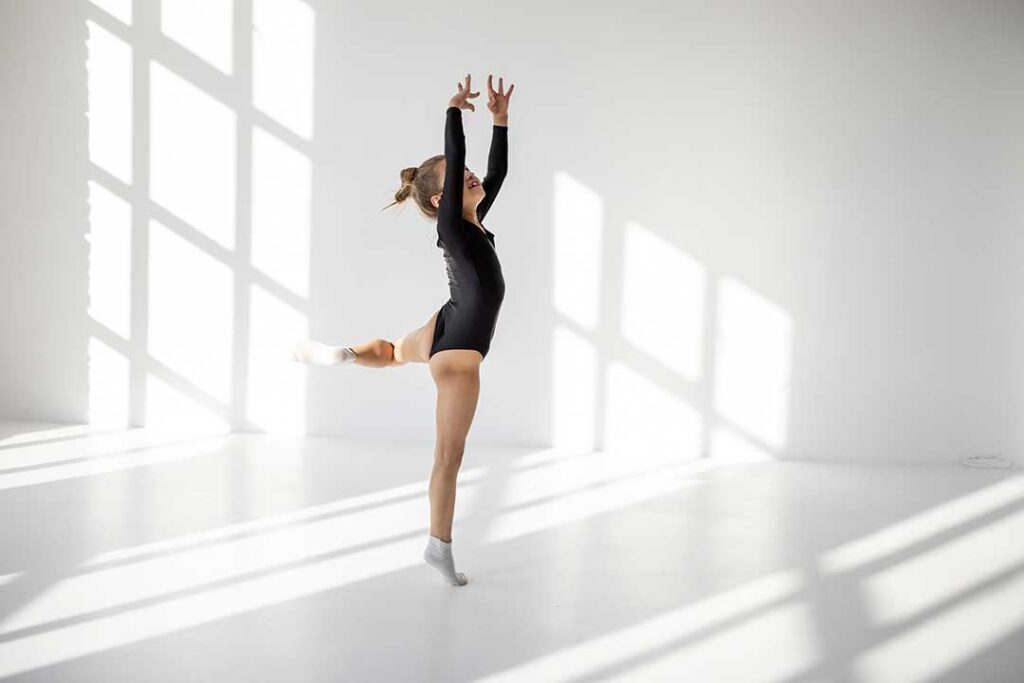 A diverse group of people of different ages dancing together in a bright studio, smiling and engaged in movement.