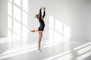 A diverse group of people of different ages dancing together in a bright studio, smiling and engaged in movement.