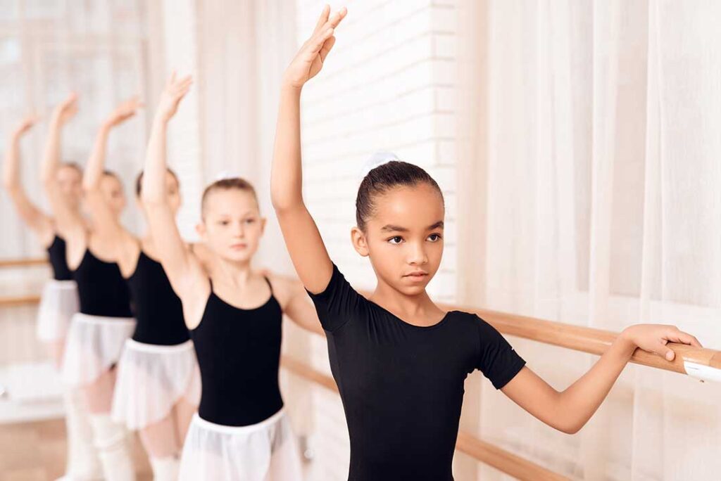 Parent helping a child organize dance shoes and clothing before class.