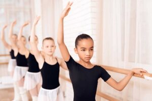 Parent helping a child organize dance shoes and clothing before class.