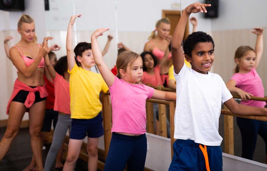 Beginners follow an instructor through simple dance steps in a bright studio.